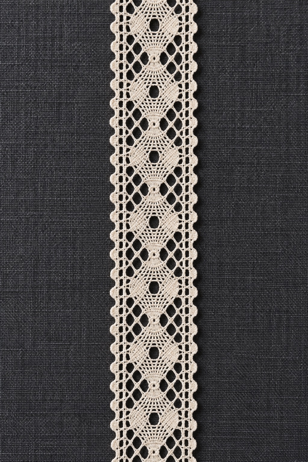 Illustrative cream geometric lace photographed against dark linen